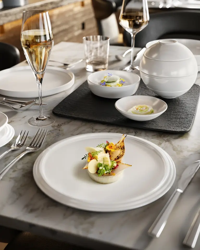 Villeroy & Boch: ZOA Studio rendering of a fine-dining place setting with plated food, champagne and a lidded porcelain tureen